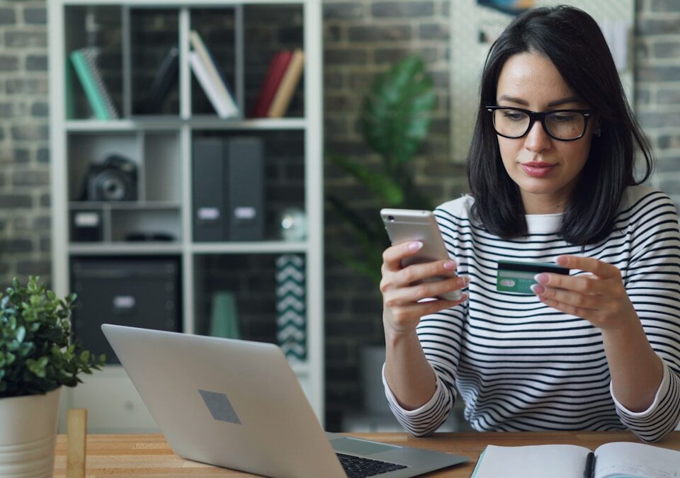 Como um servidor VPS pode melhorar seu e-commerce a woman sitting at a table looking at her cell phone