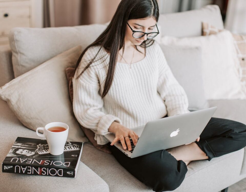 Logística de e-commerce para livros: desafios e soluções Young woman typing on laptop on sofa
