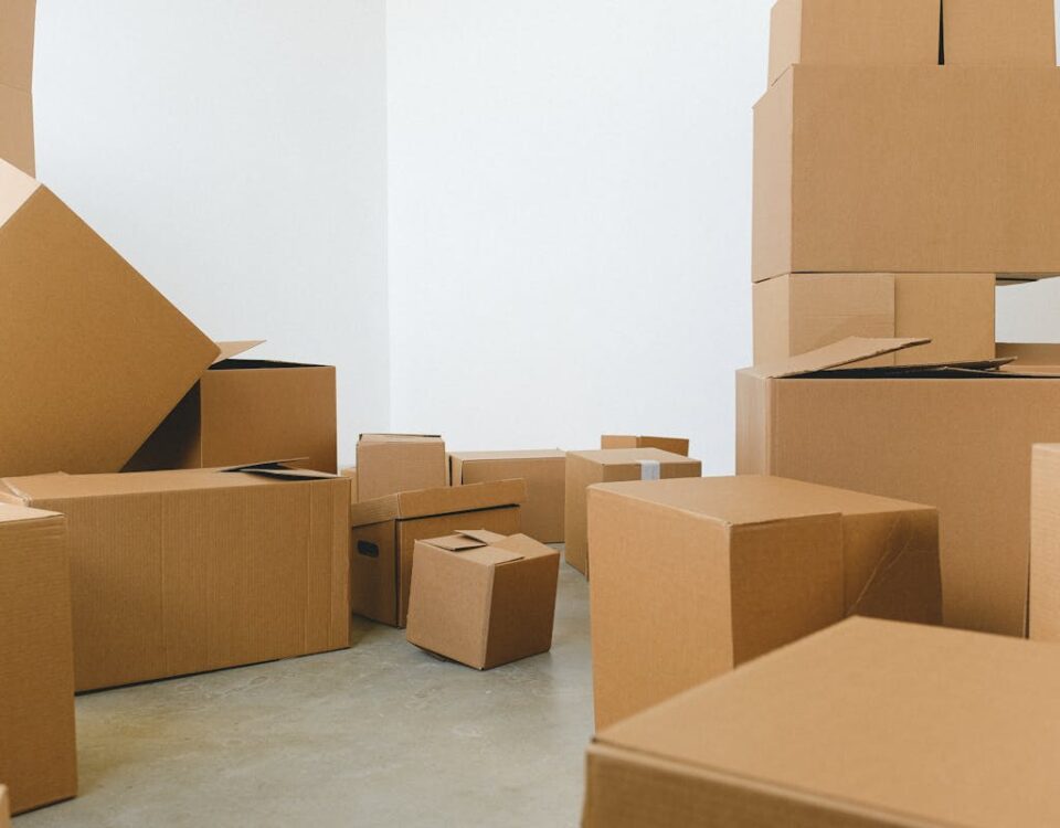 A logística por trás do sucesso das embalagens de papelão Stack of carton boxes of various shapes and sizes scattered in floor near white walls during relocation