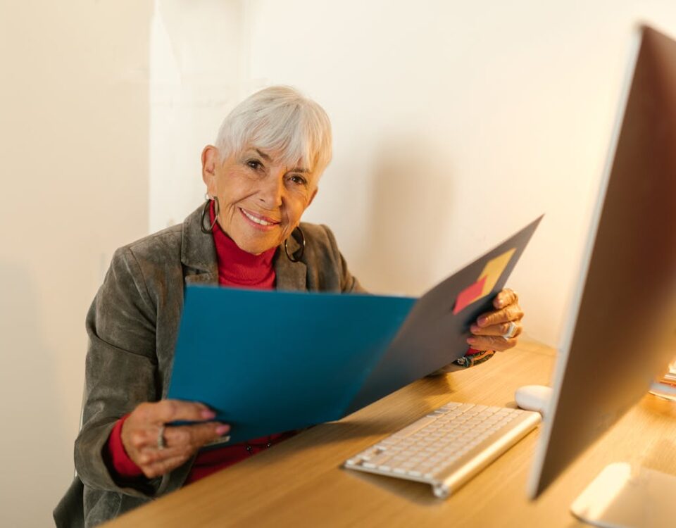 Como o comércio eletrônico de crédito consignado está mudando o mercado Gray Haired Woman Holding a Blue Folder