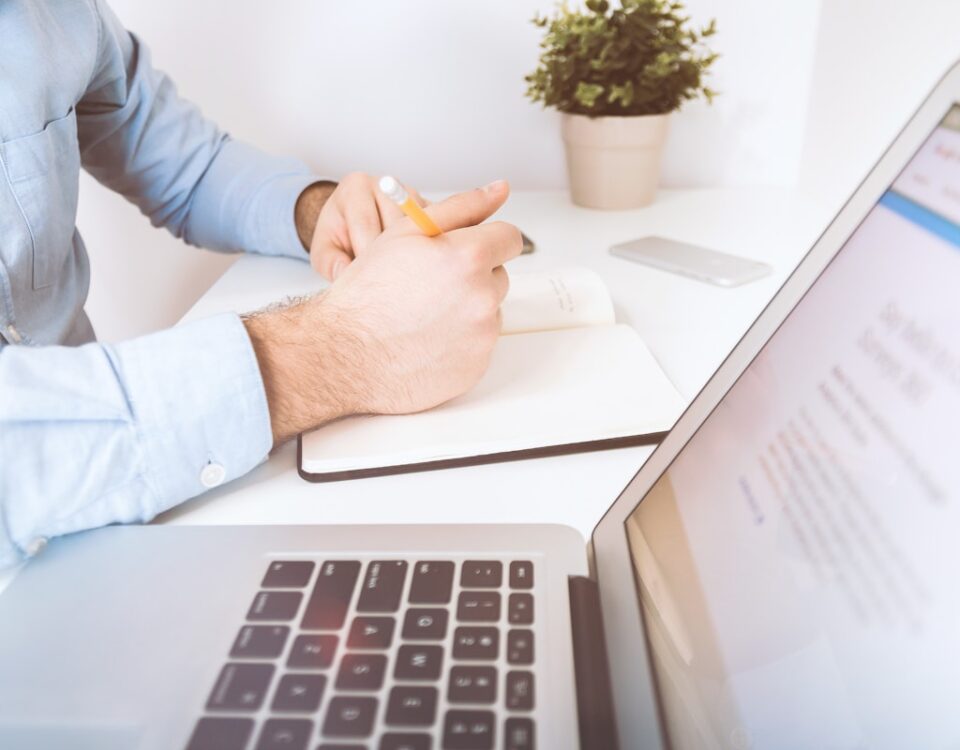 Estratégias para negociar o preço de imóveis online person writing on white notebook