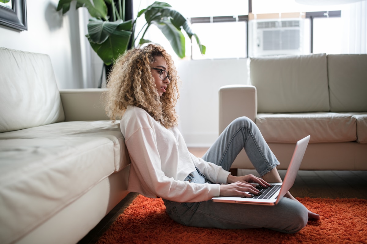 Cursos livres de e-commerce que podem alavancar seu negócio woman sitting on floor and leaning on couch using laptop