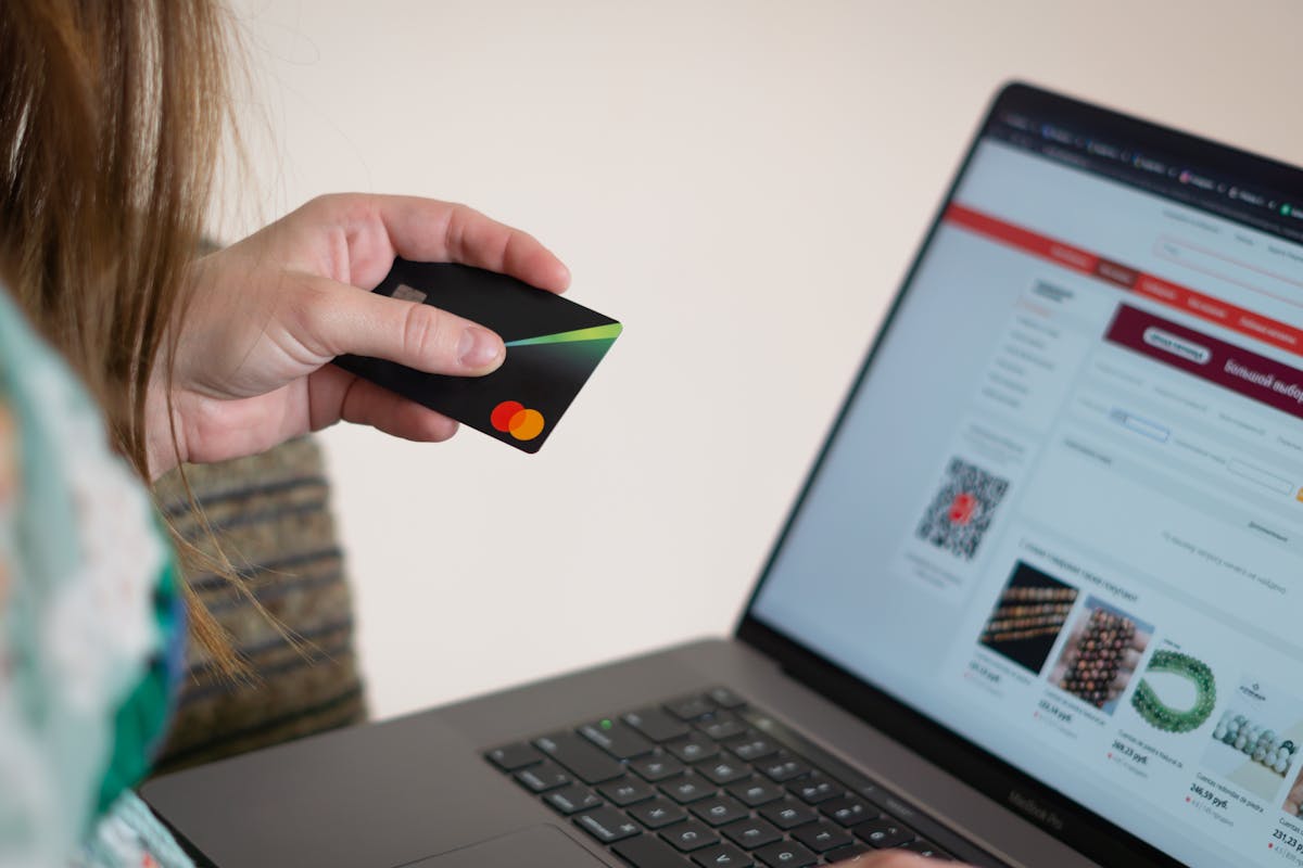 Como evitar problemas nas compras online de produtos caros Woman holding credit card while shopping online, showcasing e-commerce convenience.