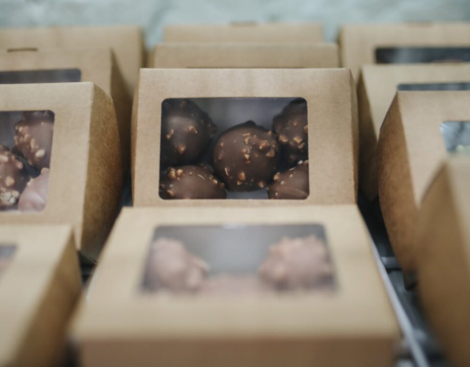 Como escolher as melhores embalagens para o delivery? Close-up of assorted chocolates packaged in cardboard boxes for sale.