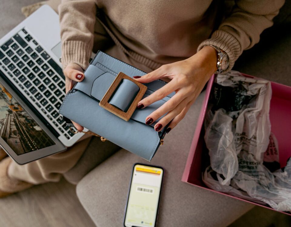Moda online e autoconhecimento: Personalização está em alta? Woman Sitting on a Couch with a Laptop on Her Lap and Holding a New Purchase