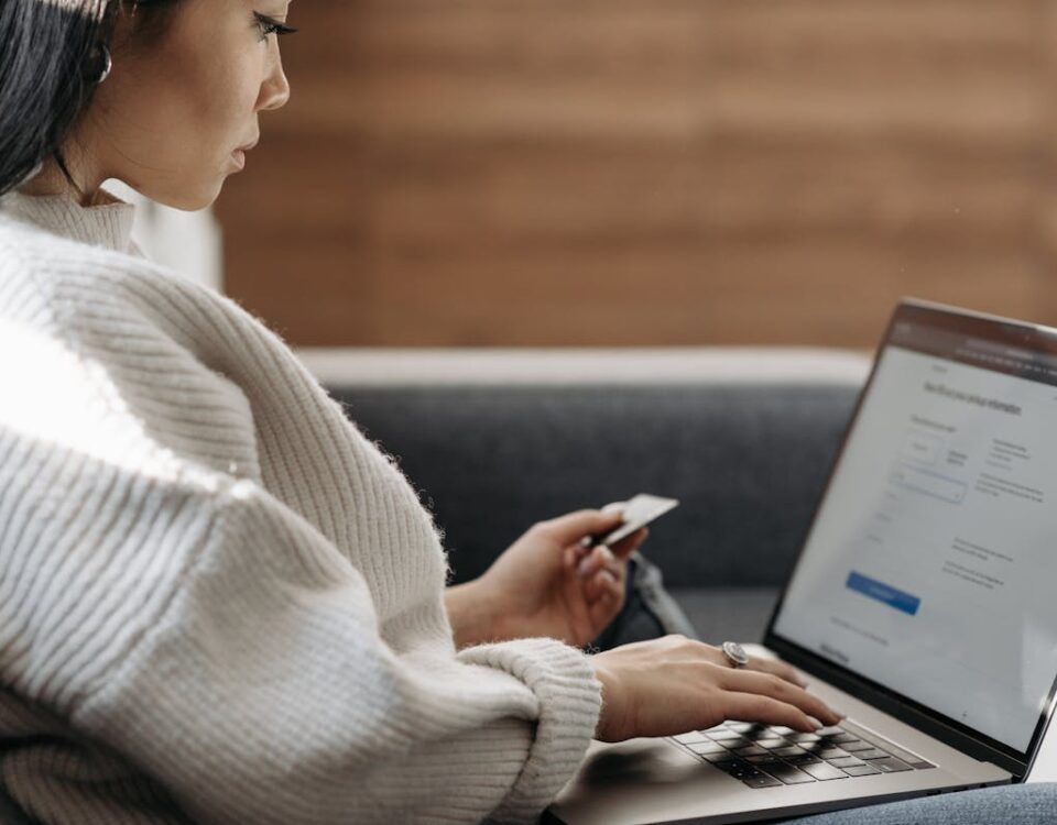Woman in White Sweater Entering Card Details into Laptop