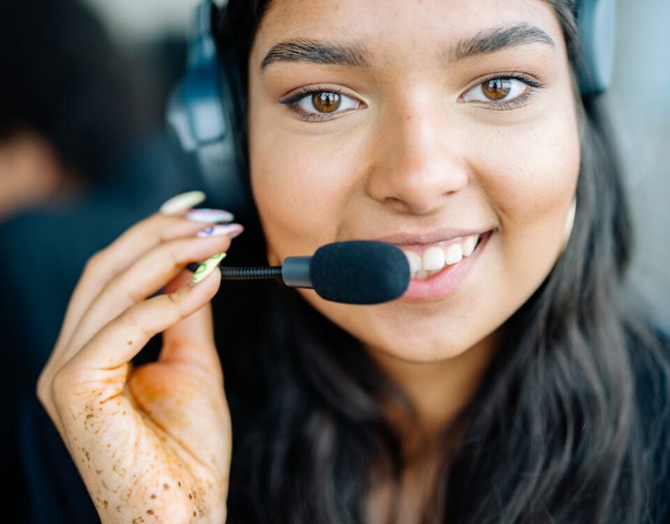 A Importância do Atendimento ao Cliente Durante o Período de Alta Demanda Charming call center operator with a headset, smiling while assisting customers.