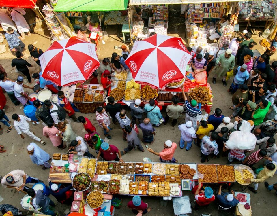 O impacto das notícias no comportamento do consumidor Aerial view of a lively street market with diverse people and food stalls under colorful umbrellas.