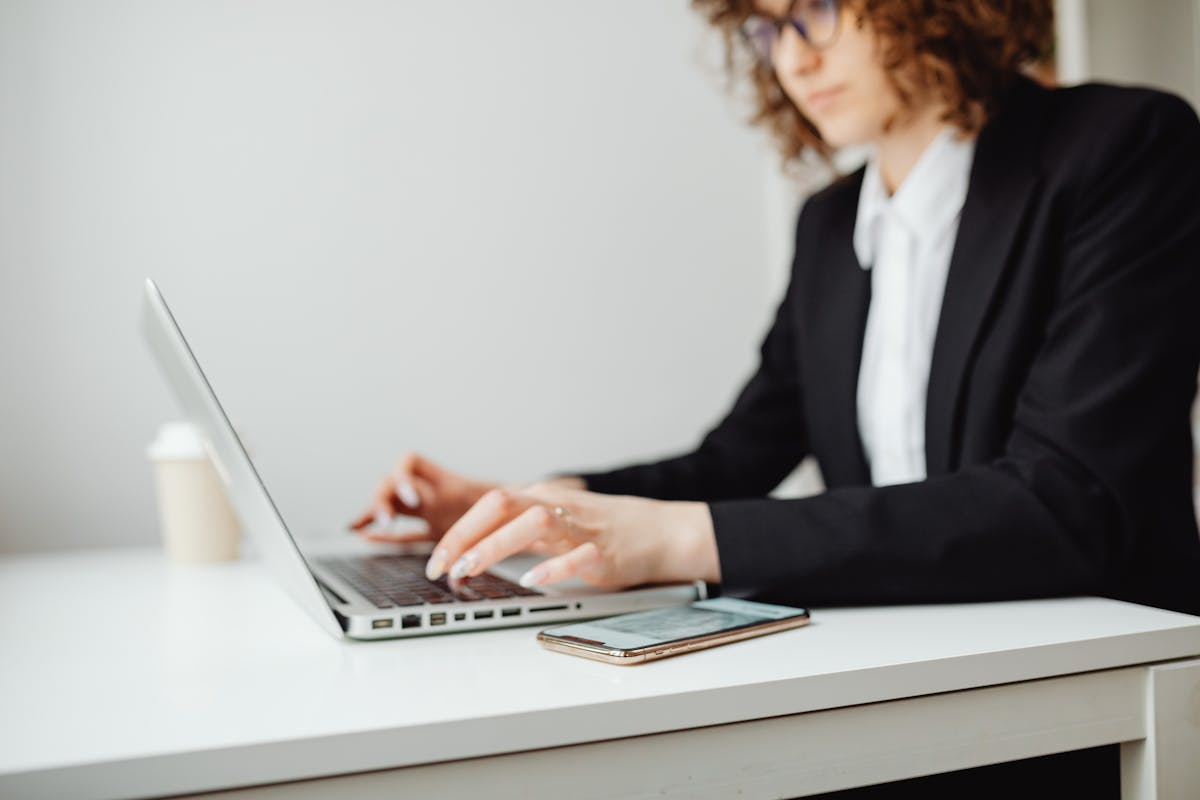 Focused businesswoman working on a laptop at a desk in a modern office.
