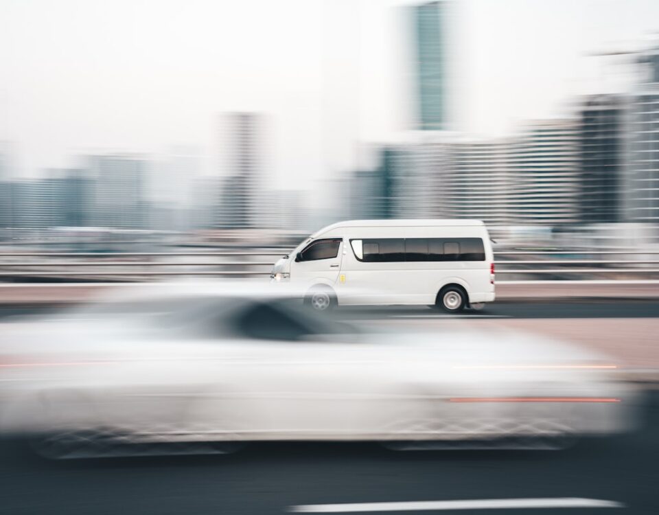 Habilidades de direção que todo entregador deve dominar a white van driving down a street next to tall buildings
