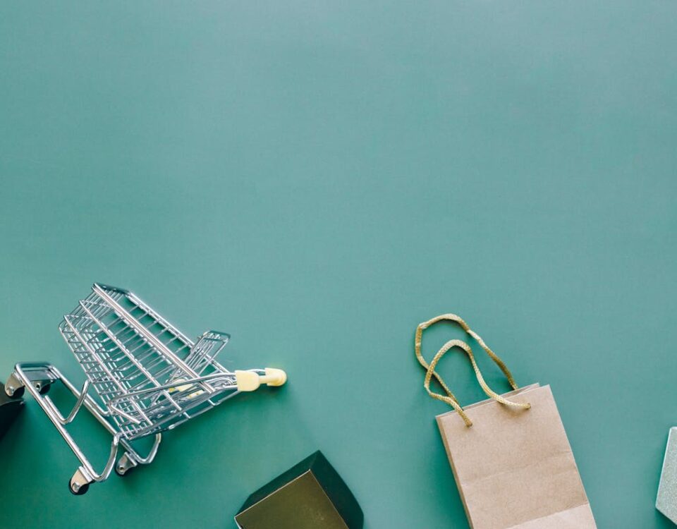 Agências criativas e estratégias para alavancar e-commerces Top view of a shopping cart and bag on a blue background, ideal for retail themes.