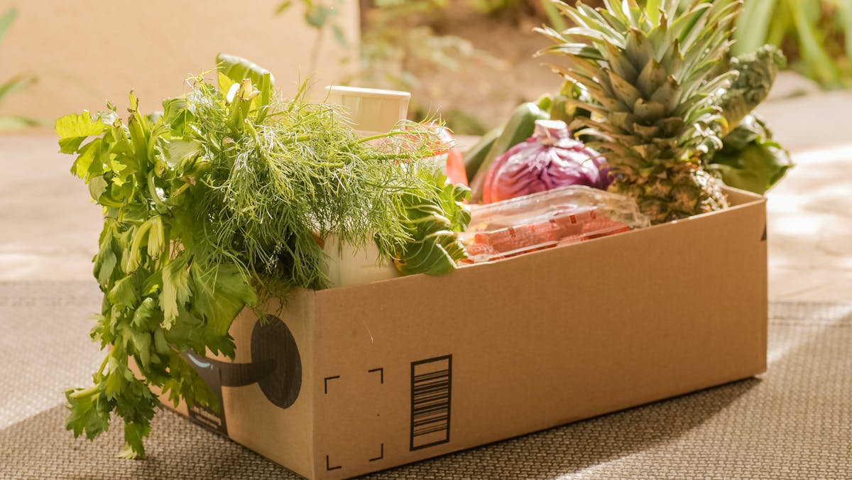 A cardboard box filled with fresh vegetables and fruits, perfect for delivery or online shopping.