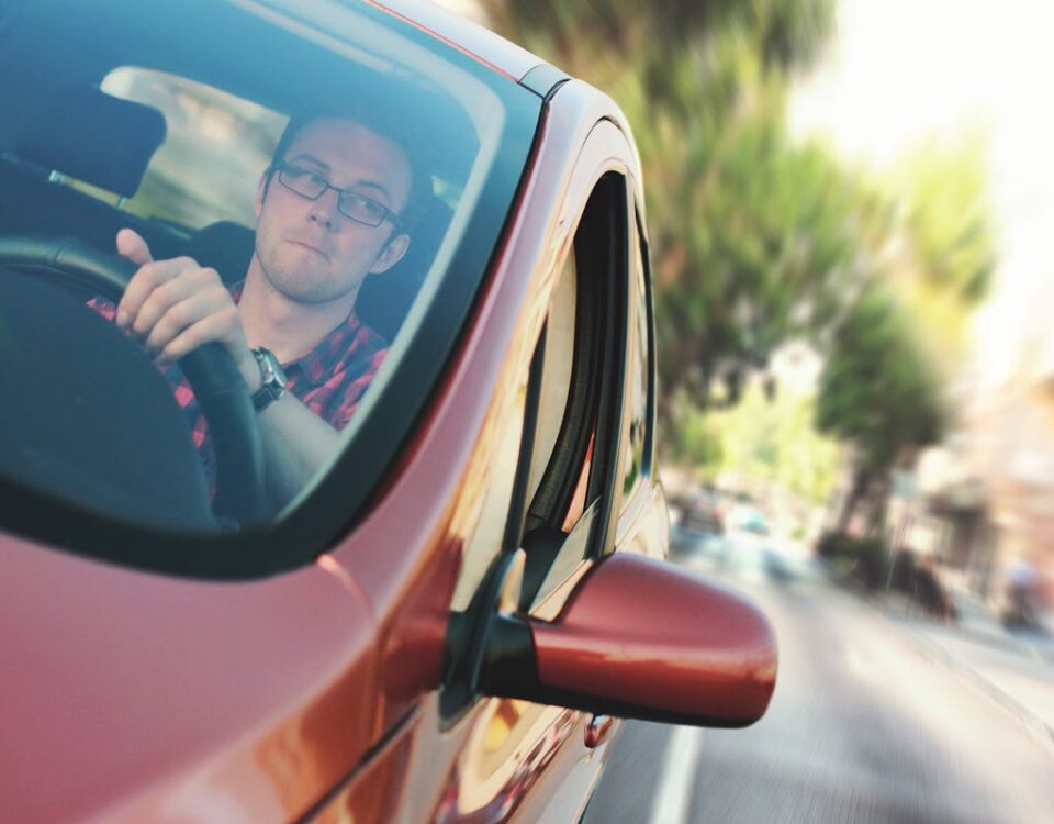 Direção econômica: um diferencial no mercado de entregas A man driving fast through a city street in a red car, showcasing motion and focus.