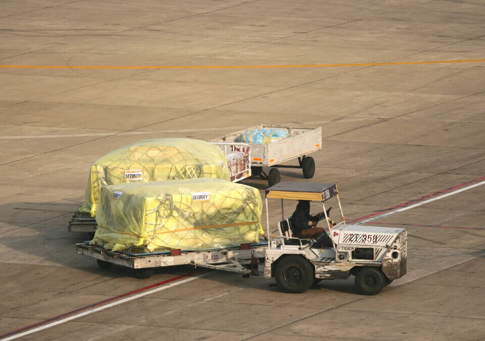 Vista aérea de carga sendo movimentada na pista de um aeroporto