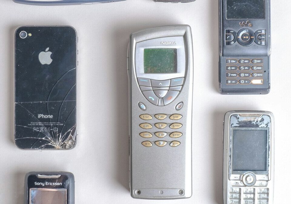 Celulares antigos de vários modelos e cores sobre superfície branca