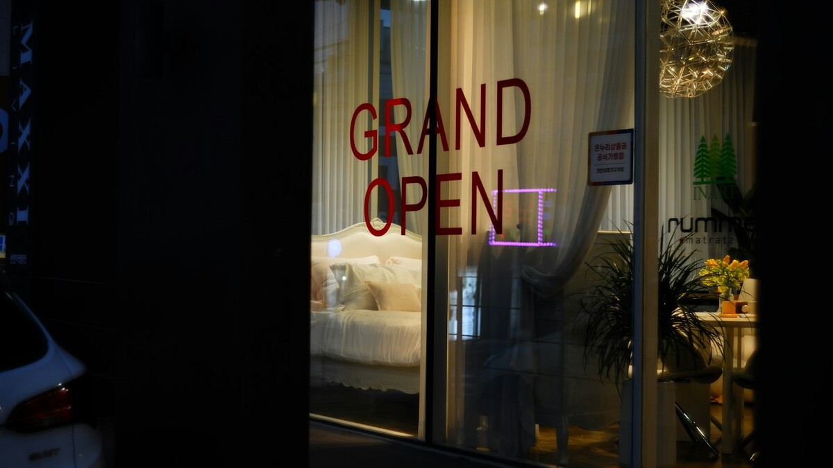 Vitrine de loja nova iluminada com aviso de inauguração no vidro