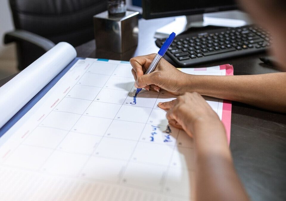 Pessoa organiza compromissos em um calendário de mesa