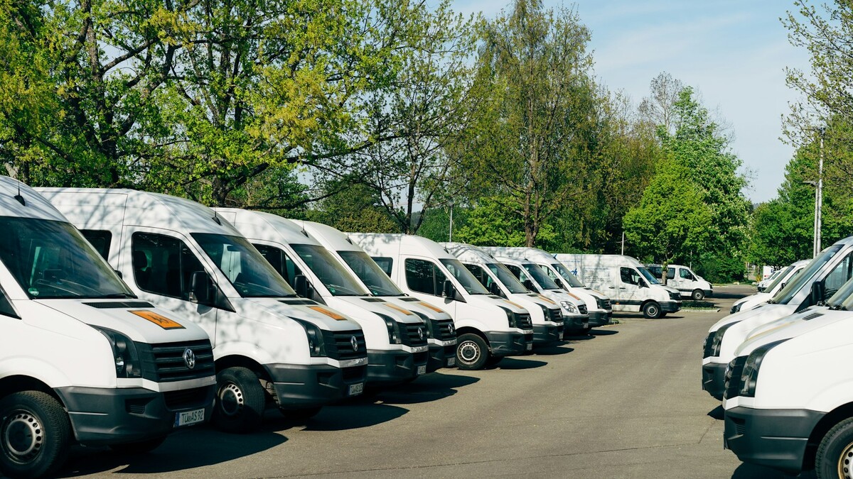 Renovar a frota: consórcio, financiamento ou leasing compensa? Fileira de vans brancas estacionadas em um pátio
